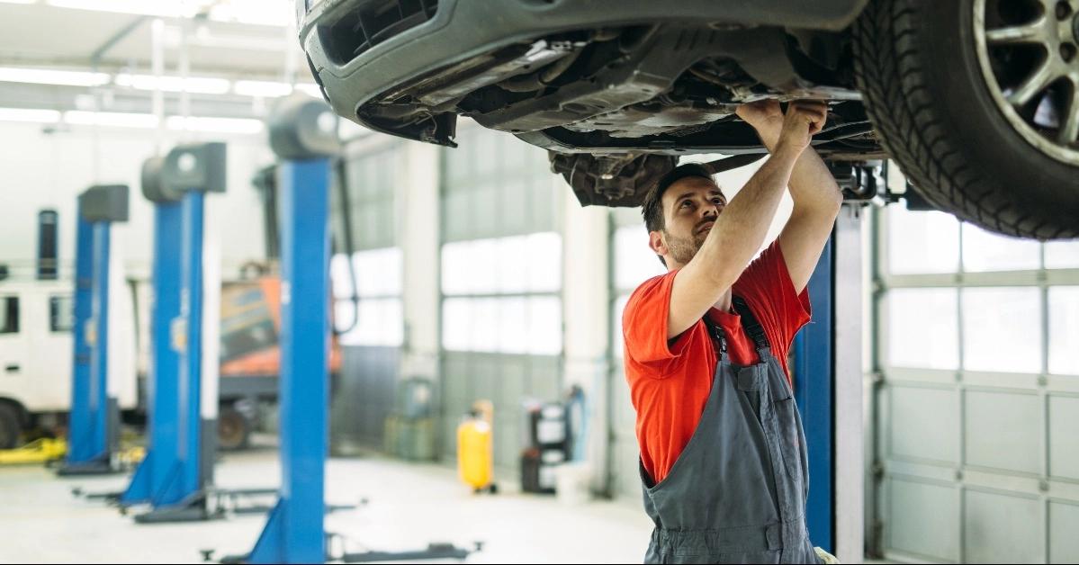 A Monterey Motor Cars technician repairing a vehicle raised on a lift in the service center