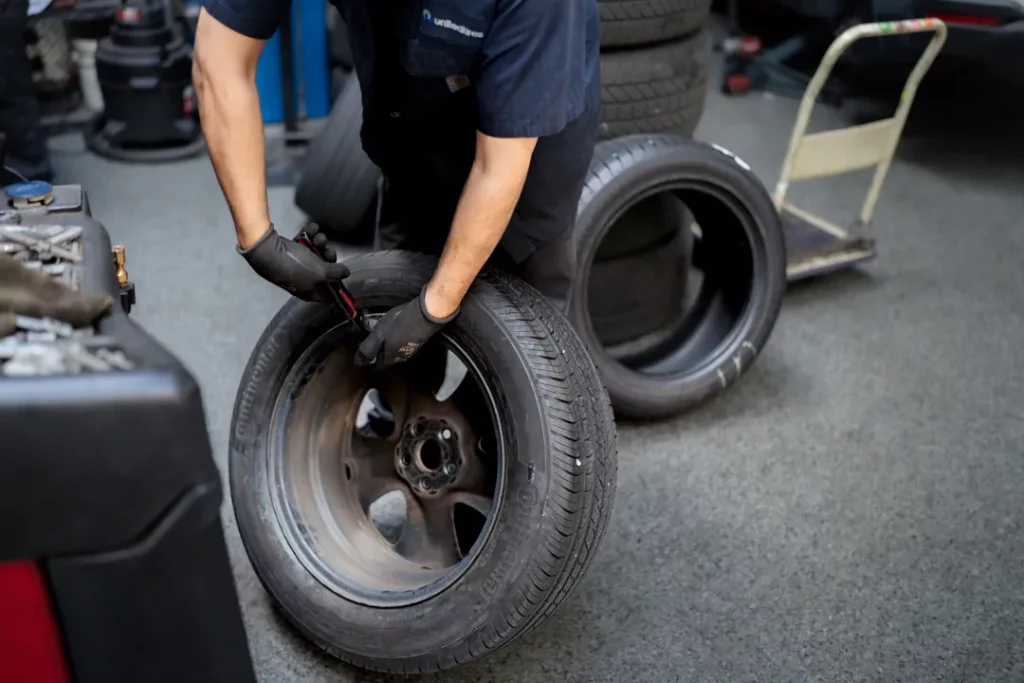 A technician fitting a new tire to a wheel in the Monterey Motor Cars service center